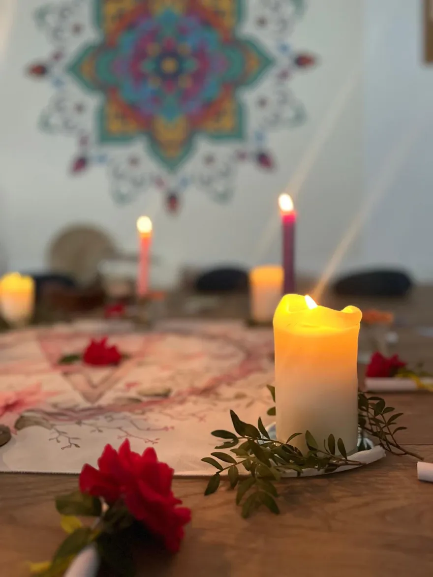 Bougies, roses et tissus au centre du cercle de femmes, devant le mandala de la salle