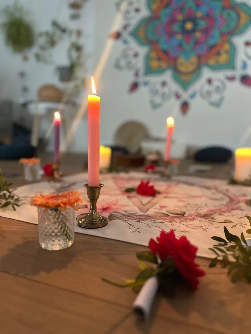 Bougies, fleurs et tissu rituel au centre du cercle, devant le mandala de la salle